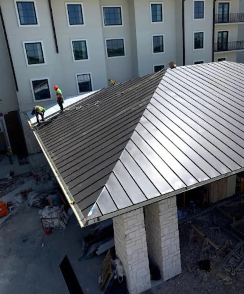 Crew installing standing seam metal roof panels on a commercial project in Crozet